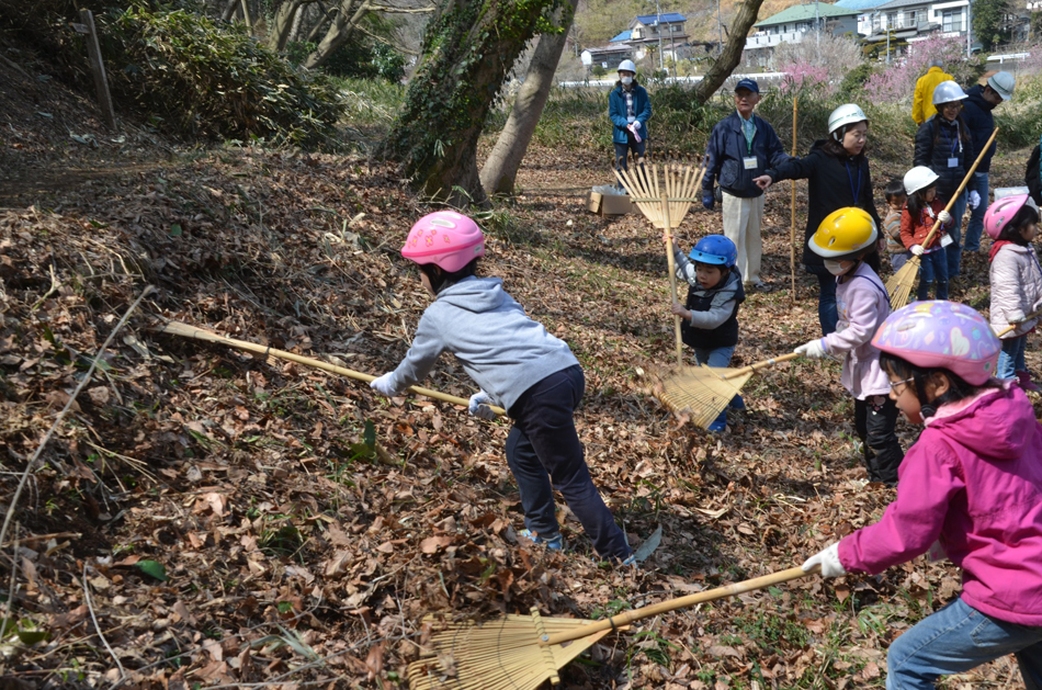 里山体験イベントで落ち葉をかき集める子どもたち